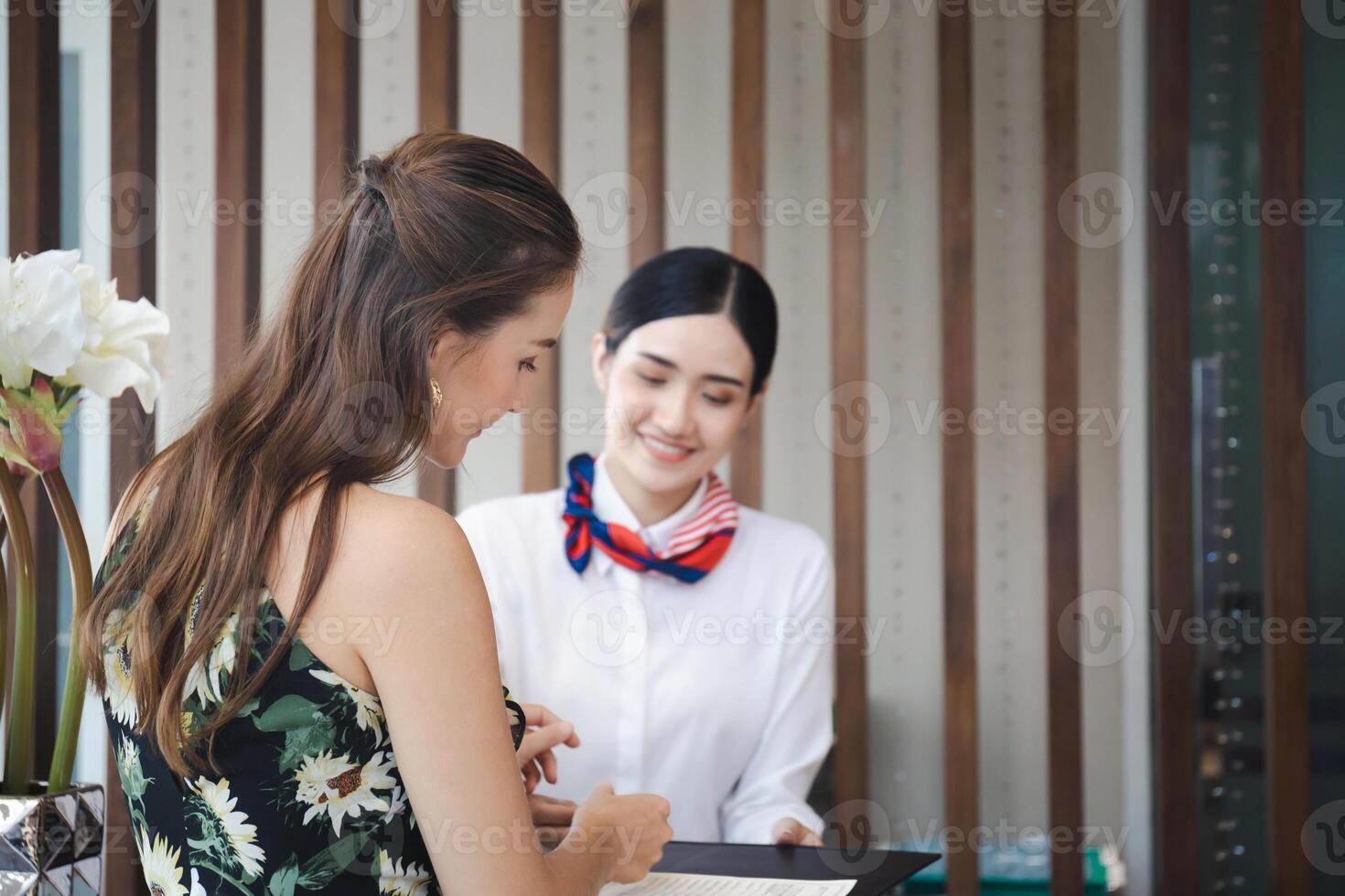 focus Aan vrouw reizigers met zak reizen bagage Check in Bij de hotel met wazig glimlachen vrouw receptioniste foto