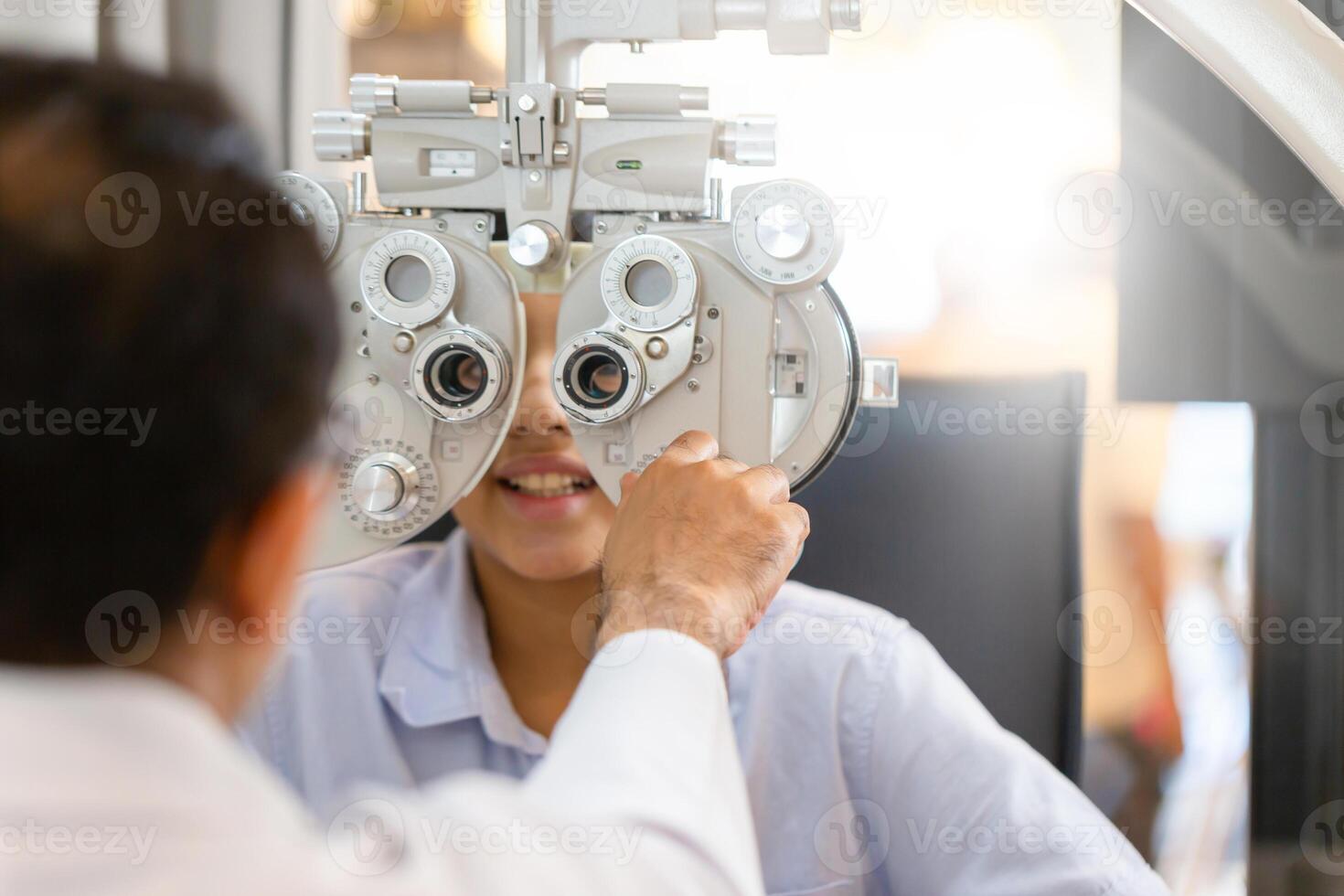 optometrist aan het doen zicht testen voor kind geduldig in kliniek, Indisch kind kiezen bril in optiek op te slaan, jongen aan het doen oog test controle examen met optometrist in optisch winkel foto