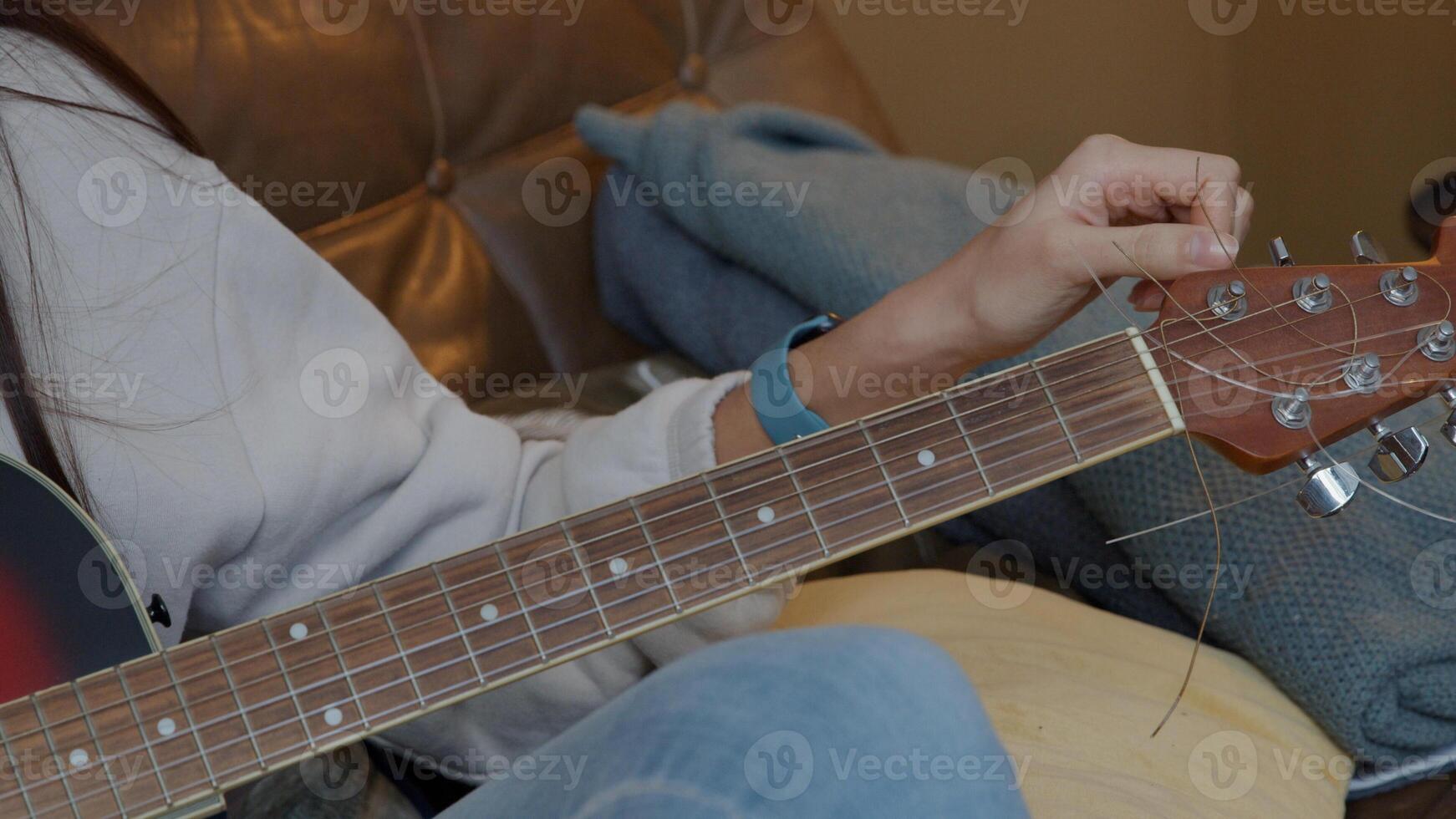 hand met mobiele telefoon van jonge Midden-Oosten man houden voor gitaar van jonge gemengd ras vrouw, tuner van gitaar draaien foto