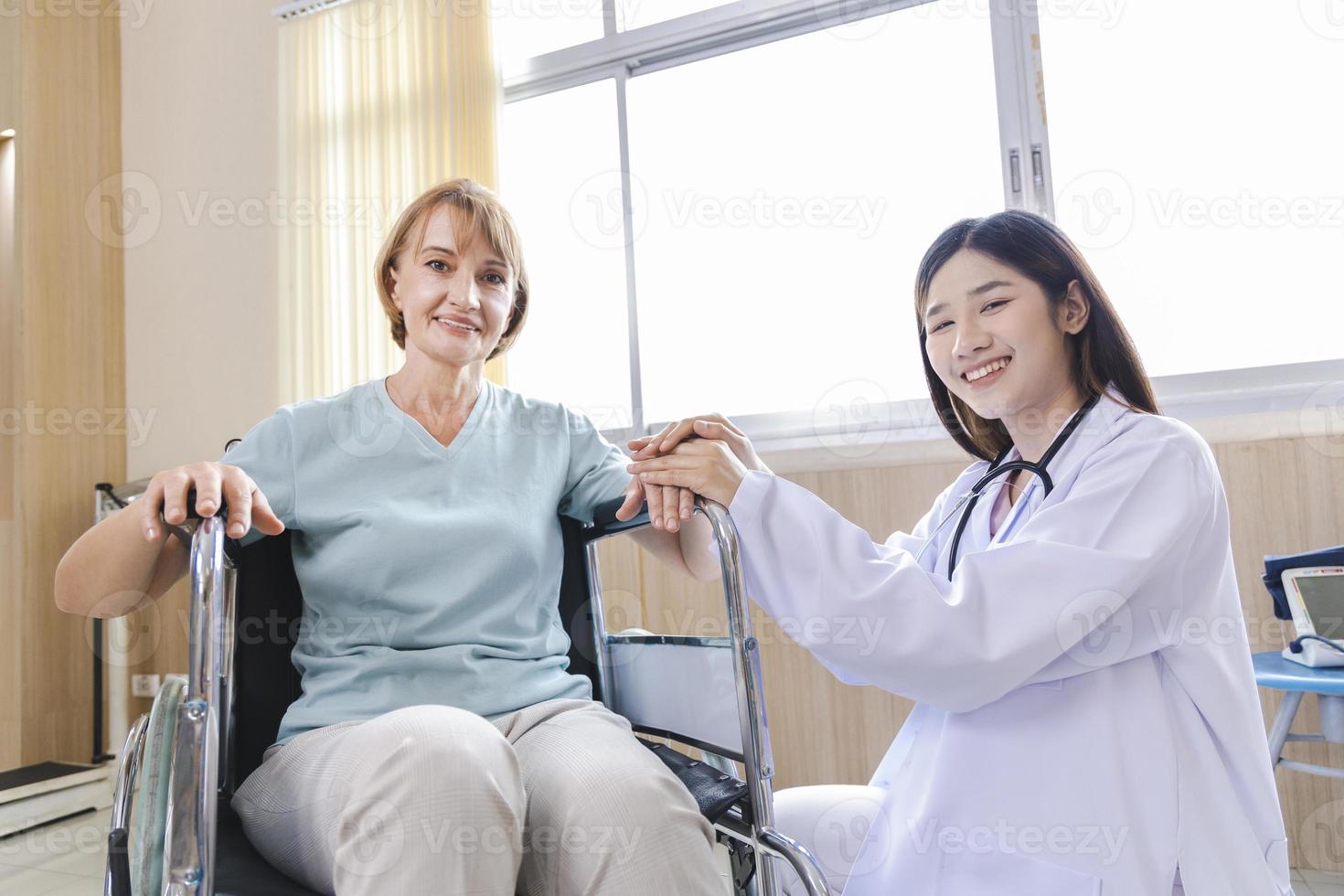 vrouwelijke arts geeft advies en moedigt de oude vrouwelijke patiënt in een rolstoel aan foto