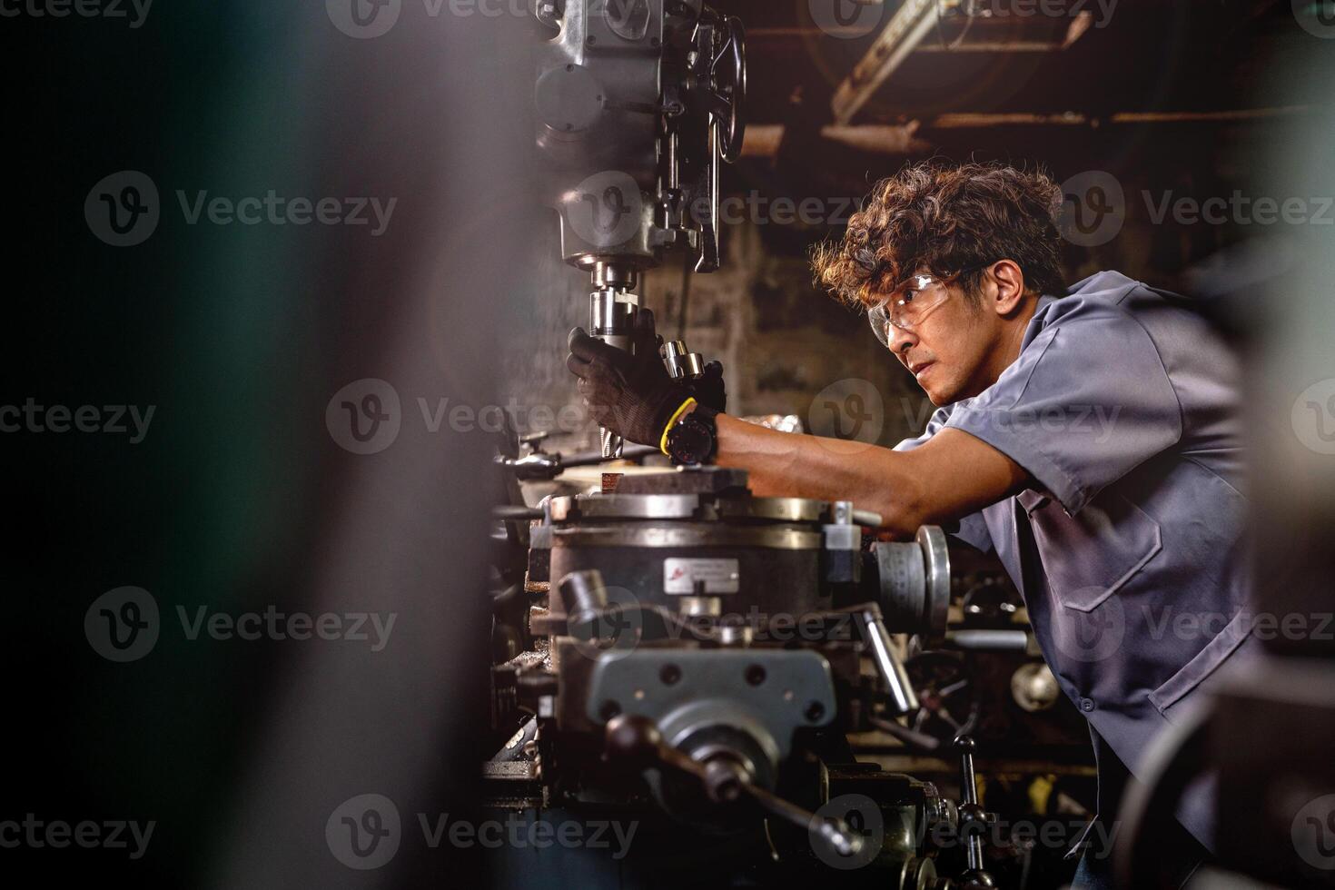 Aziatisch arbeider in productie fabriek boren Bij machine. professioneel arbeider in de buurt boren machine Aan fabriek. afwerking metaal werken intern staal oppervlakte Aan draaibank Slijper machine met vliegend vonken. foto