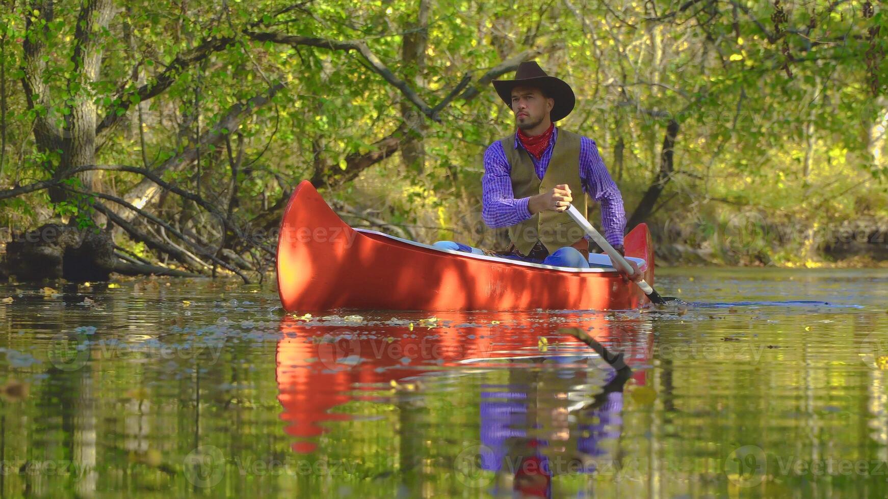 cowboy in een kano drijft Aan de rivier- in de Woud. historisch wederopbouw van leven in de wild west van Amerika foto