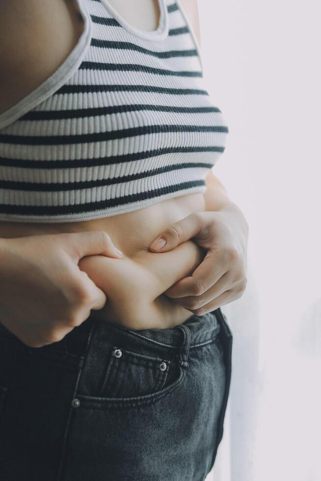 Dames lichaam dik buik. zwaarlijvig vrouw hand- Holding buitensporig buik dik. eetpatroon levensstijl concept naar verminderen buik en vorm omhoog gezond maag spier. foto