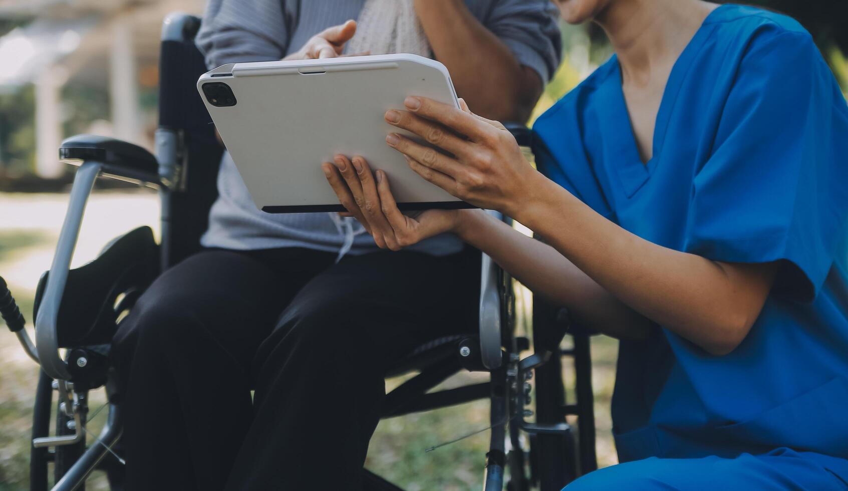 ouderen Aziatisch senior vrouw Aan rolstoel met Aziatisch voorzichtig verzorger en aanmoedigen geduldig, wandelen in tuin. met zorg van een verzorger en senior Gezondheid verzekering in zon licht foto