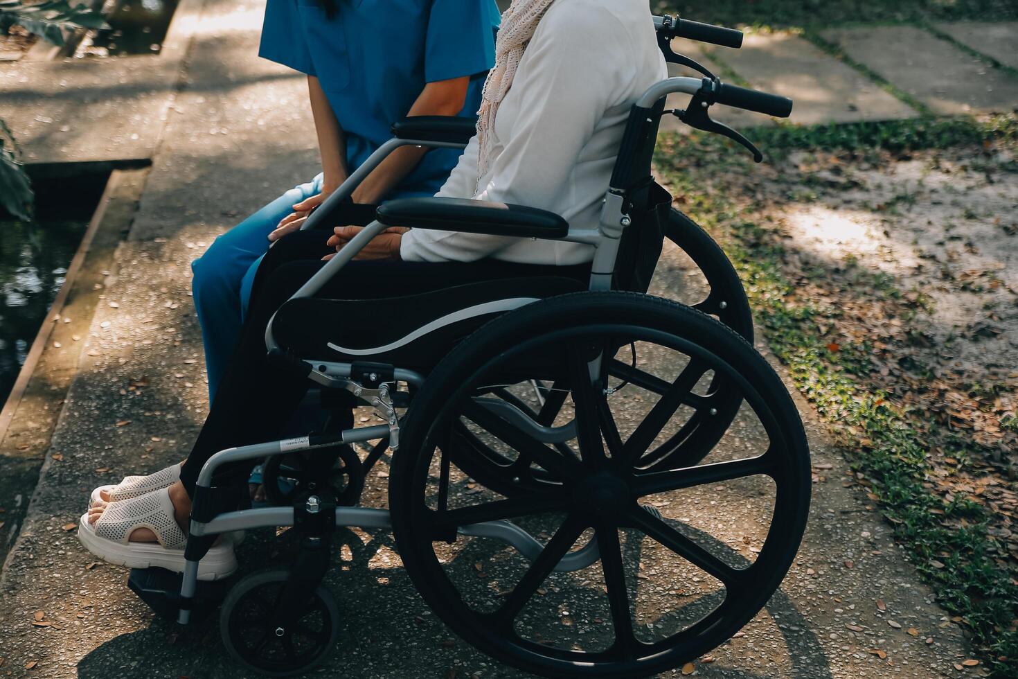 een verpleegster nemen zorg een senior mannetje Aan rolstoel in zijn tuin Bij huis foto