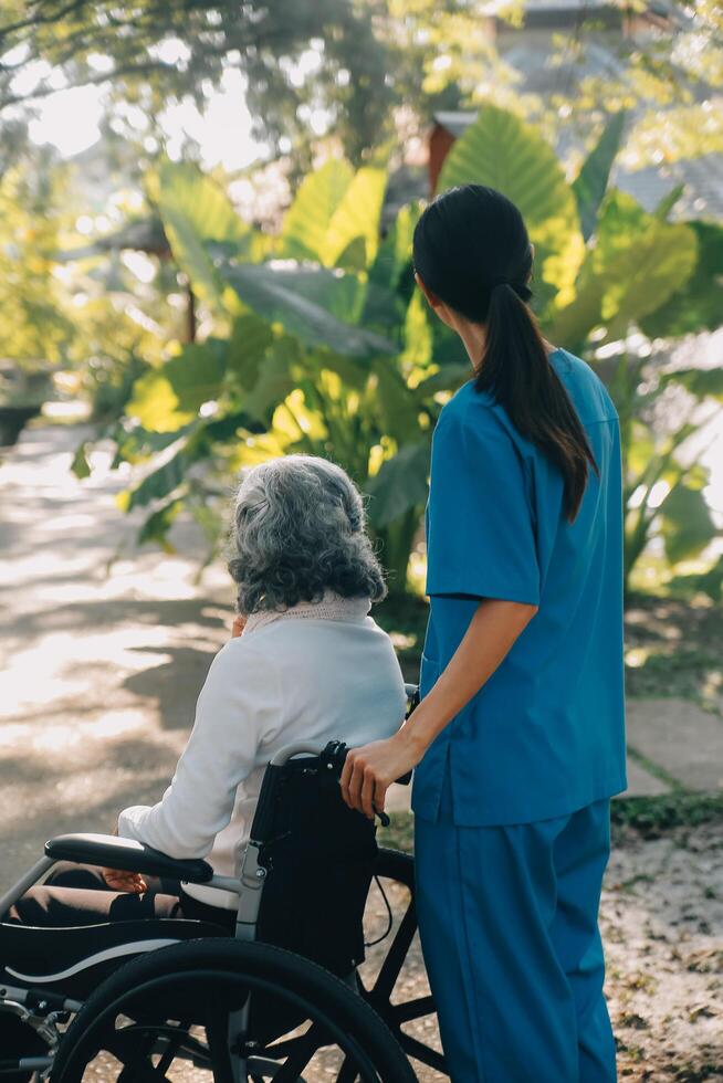 een verpleegster nemen zorg een senior mannetje Aan rolstoel in zijn tuin Bij huis foto