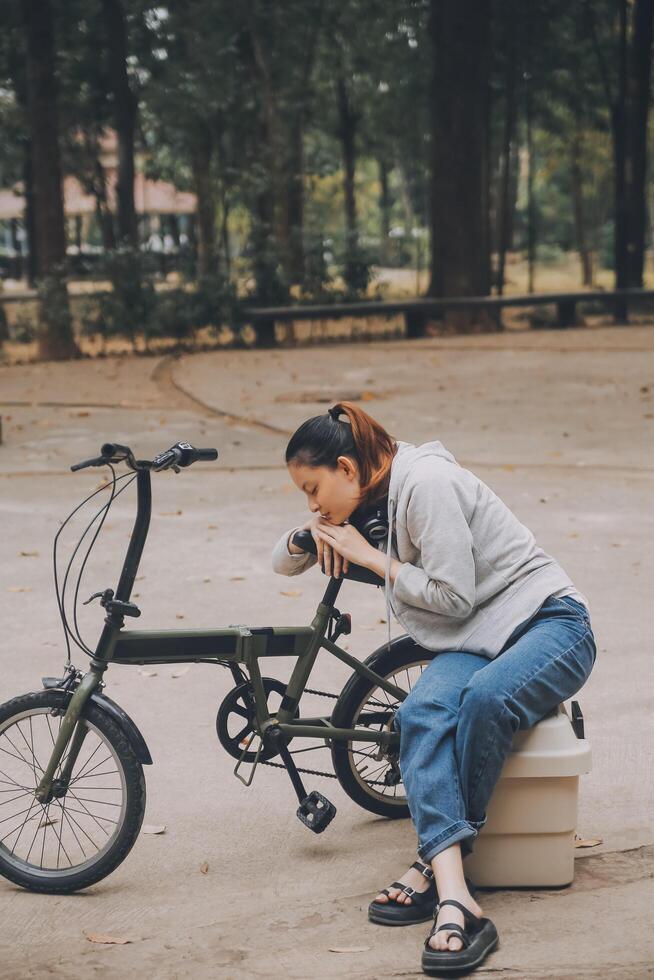 gelukkig Aziatisch jong vrouw wandelen en rijden fiets in park, straat stad haar glimlachen gebruik makend van fiets van vervoer, eco vriendelijk, mensen levensstijl concept. foto