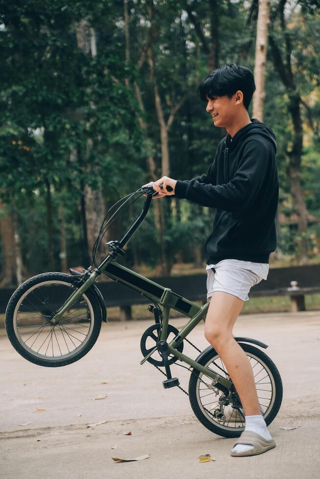 knap gelukkig jong Mens met fiets Aan een stad straat, actief levensstijl, mensen concept foto