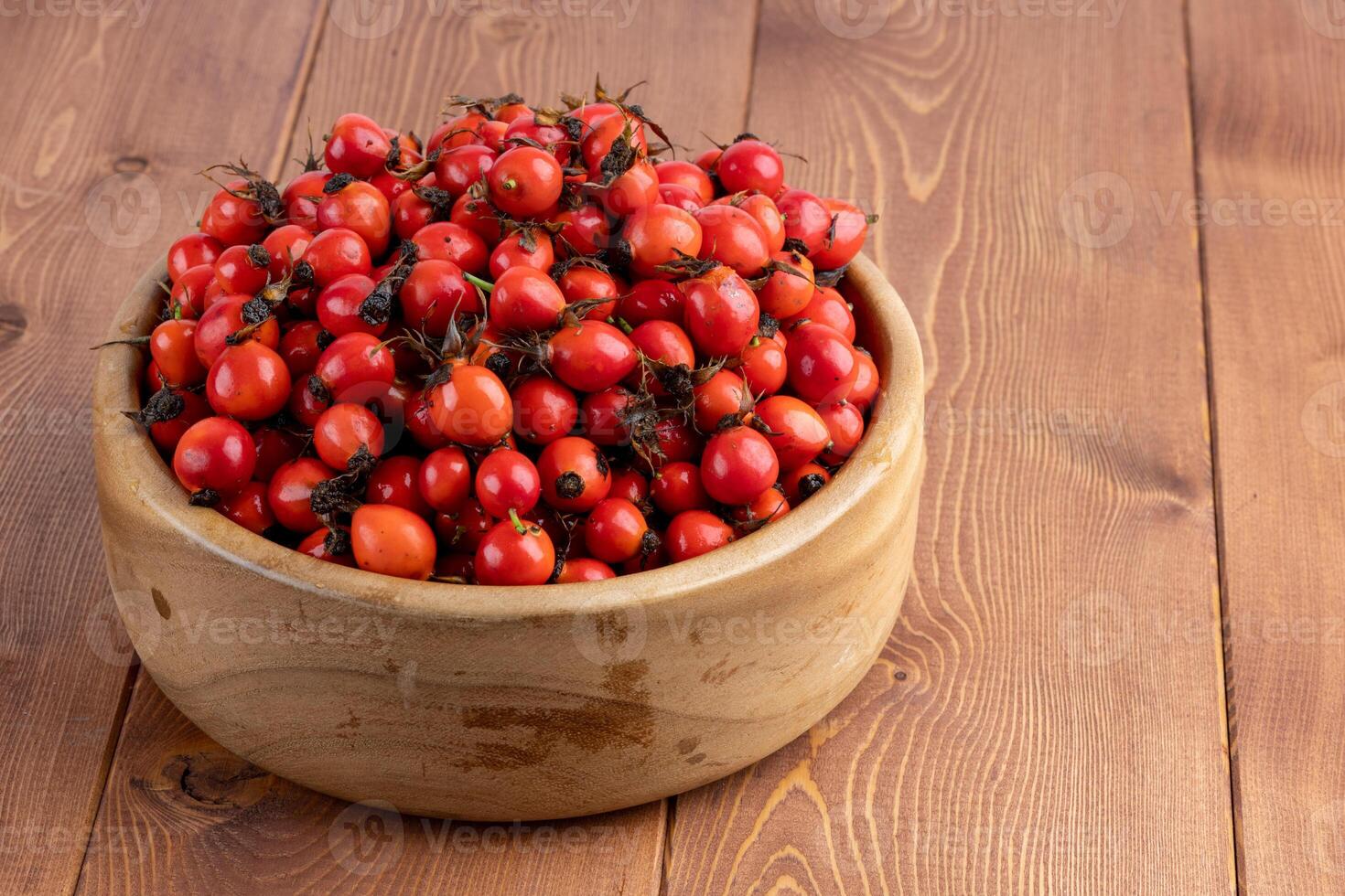 rood hondenroos rozenbottel fruit in een houten kom Aan houten tafel foto