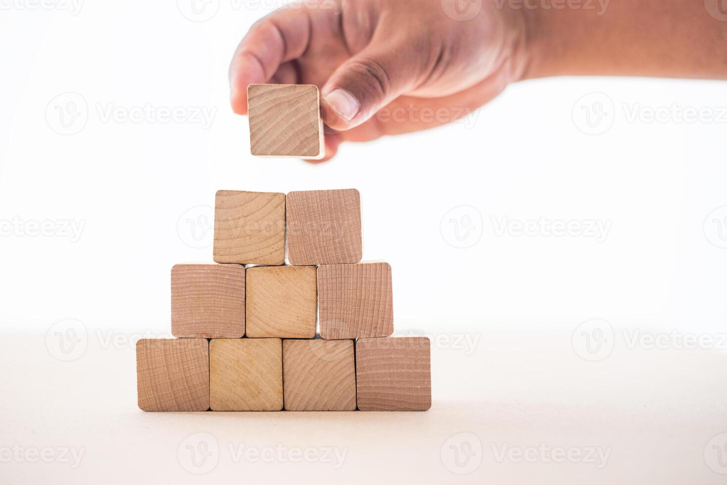 de hand- van de zakenman gevangen de houten blokken geplaatst Aan een wit achtergrond net zo een huis naar tonen de stabiliteit van aan het doen bedrijf. foto