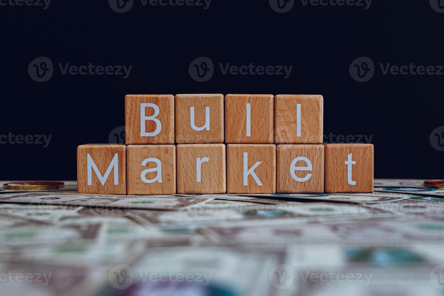 houten blokken met de tekst stier markt Aan een zwart achtergrond en crypto bankbiljetten verspreide Aan de grond. foto