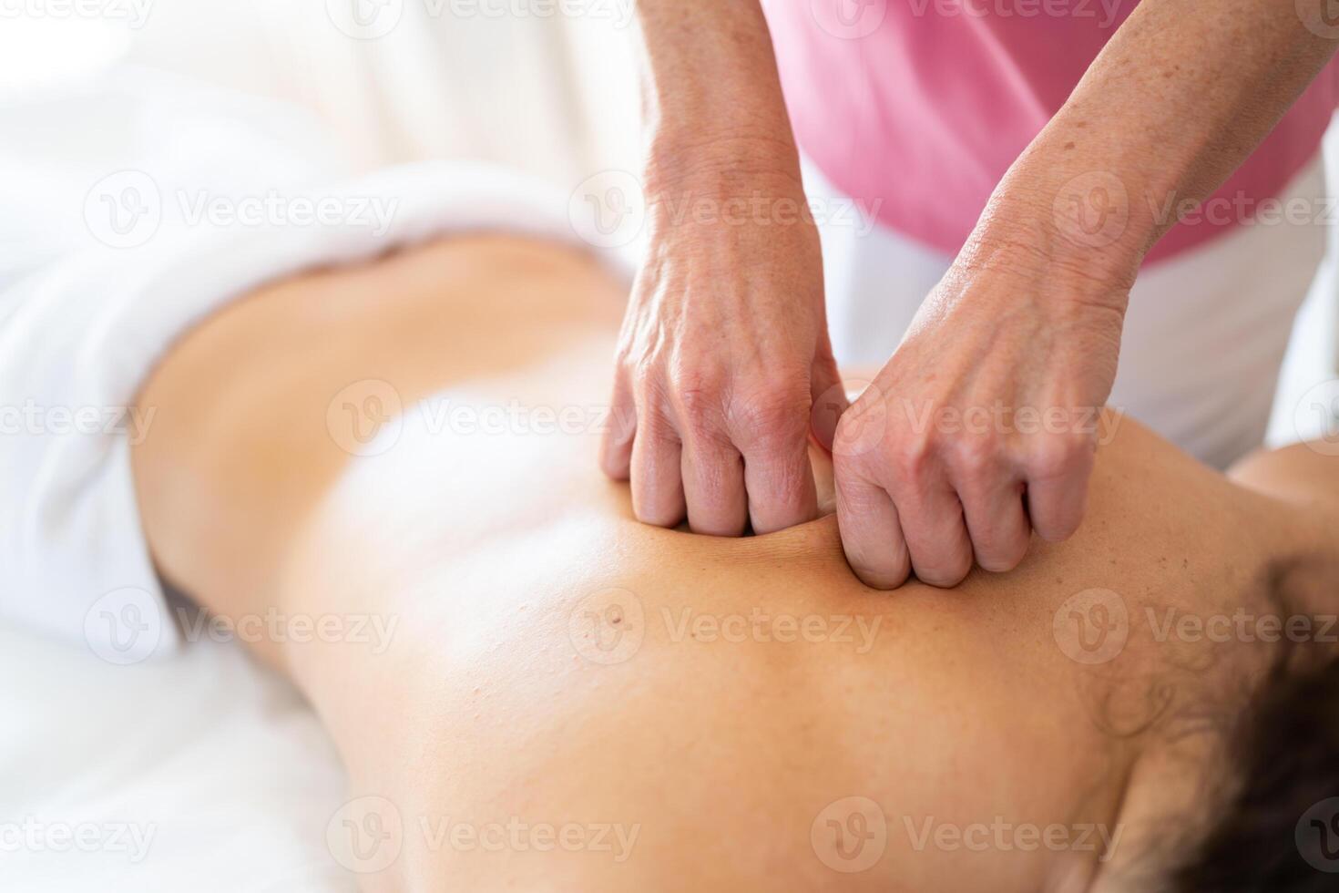 massage therapeut gebruik makend van vuisten terwijl masseren terug van vrouw geduldig foto