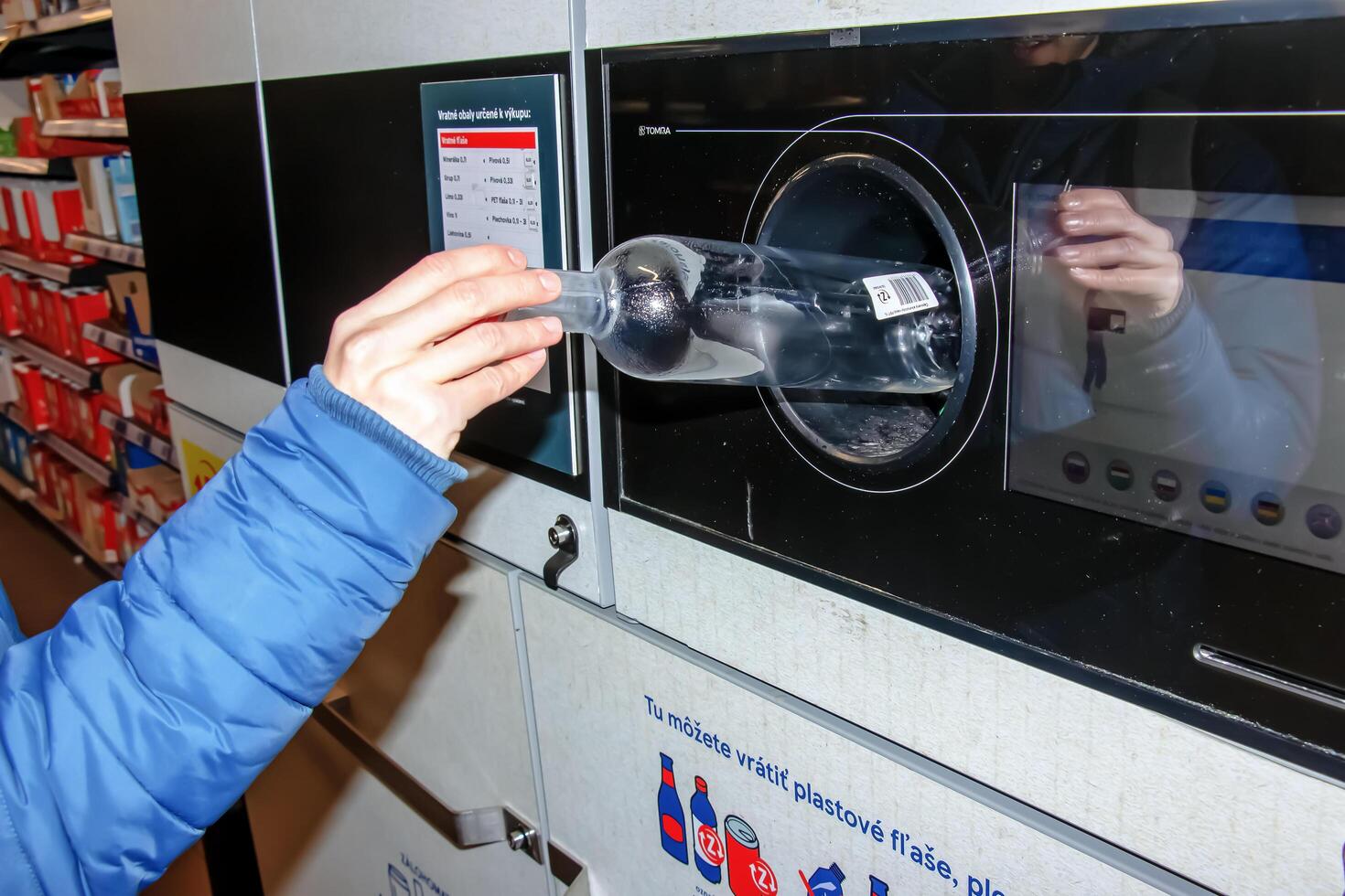 nitraat, Slowakije - 16-01-2024 detailopname van een man's hand- zetten een fles in een verspilling recycling machine. foto