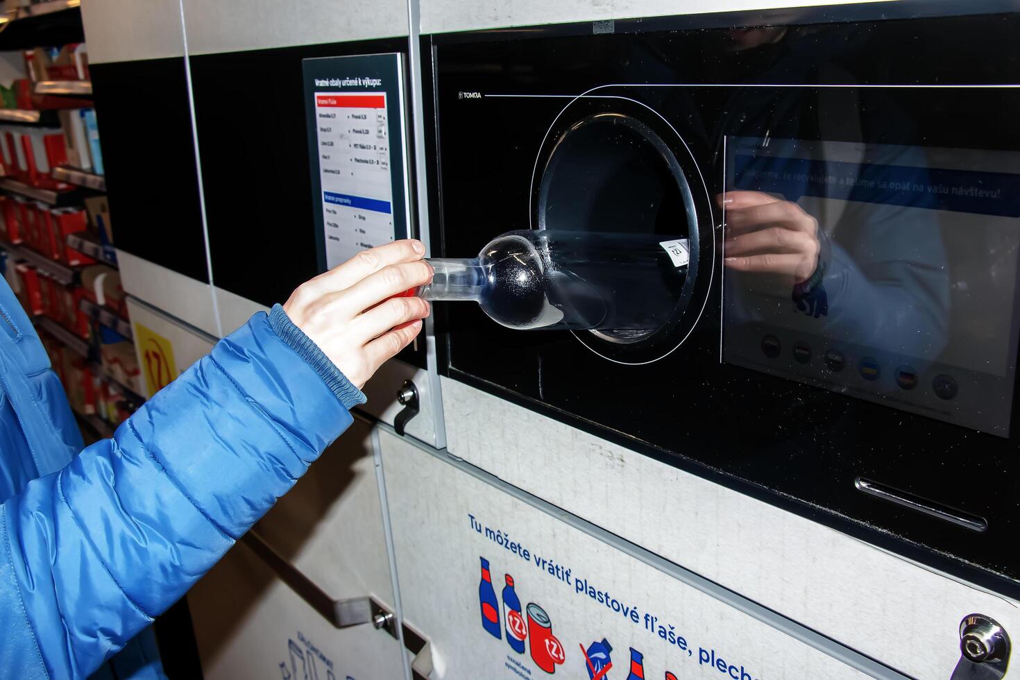 nitraat, Slowakije - 16-01-2024 detailopname van een man's hand- zetten een fles in een verspilling recycling machine. foto