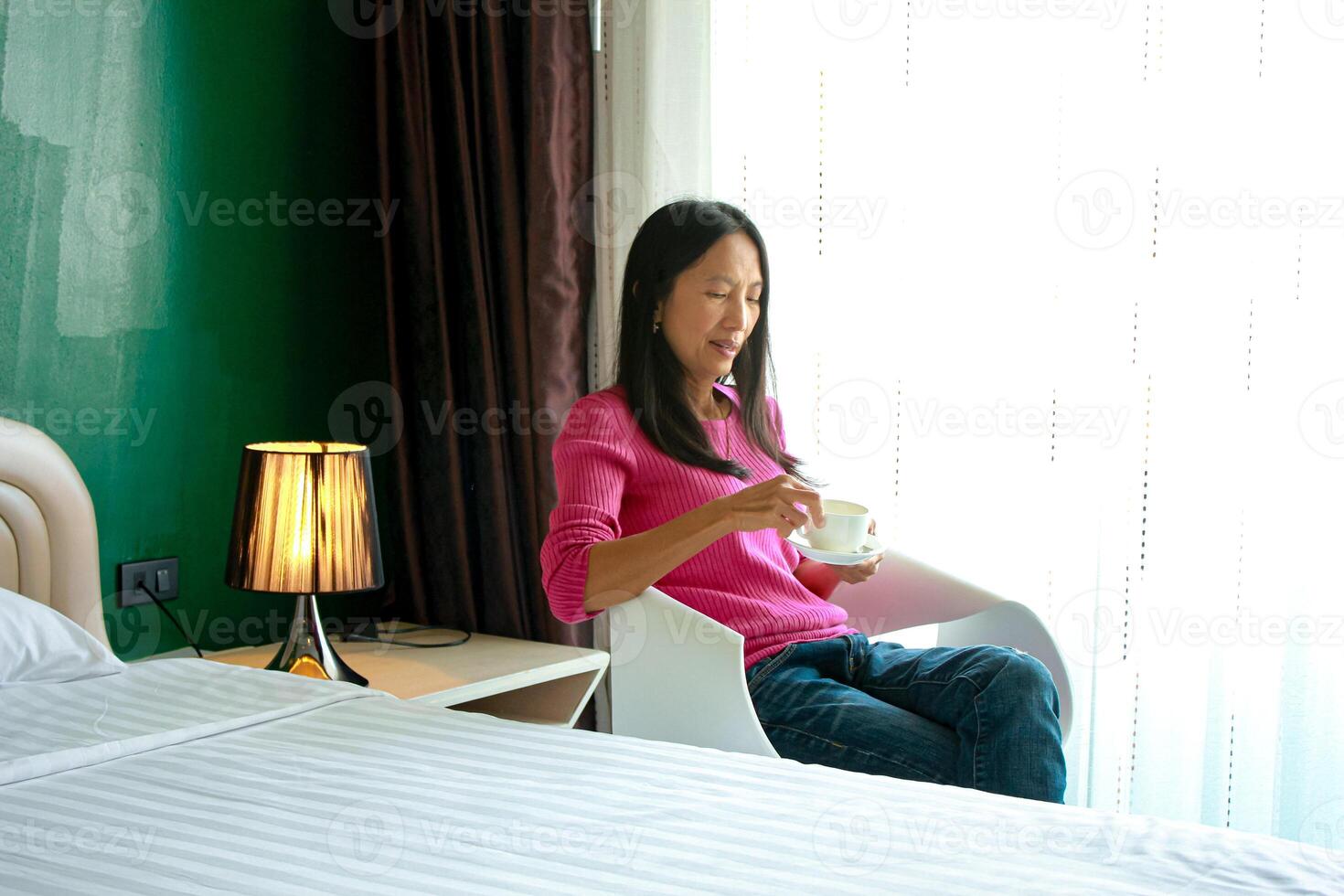 portret van mooi jong Aziatisch vrouw Holding kop van ochtend- koffie in wit slaapkamer, Vrolijk, vrolijk, ontspannende in zomer. Thais Aziatisch bedenken ideeën, wit slaapkamer foto