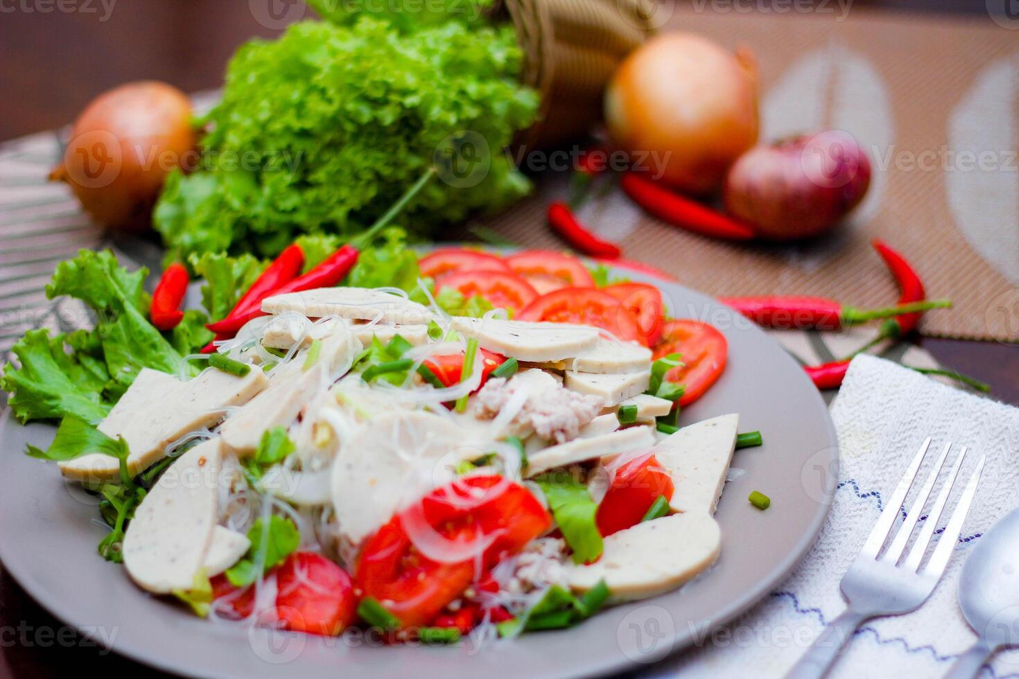 pittig glas noodle salade met Vietnamees worst geserveerd in een grijs bord zetten Aan een houten tafel en divers groenten. foto