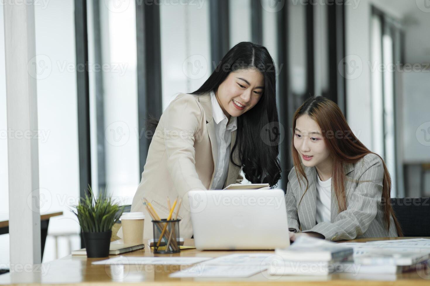 twee bedrijf Dames zijn bespreken de werk ze hebben gedaan samen en uitwisselen ideeën. naar werk naar ontwikkelen de bedrijf beter. foto