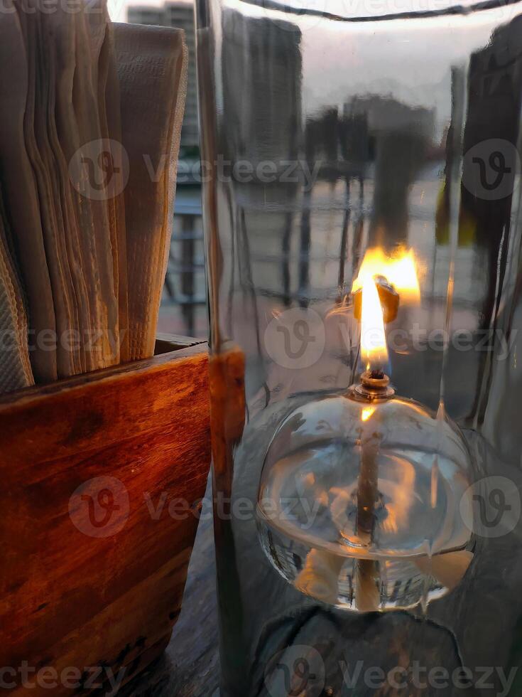 olie lantaarn bureau lamp, transparant glas, romantisch licht Aan de houten tafel, warm humeur restaurant, dichtbij omhoog, dining tafel instelling met zakdoek papier voor klant foto