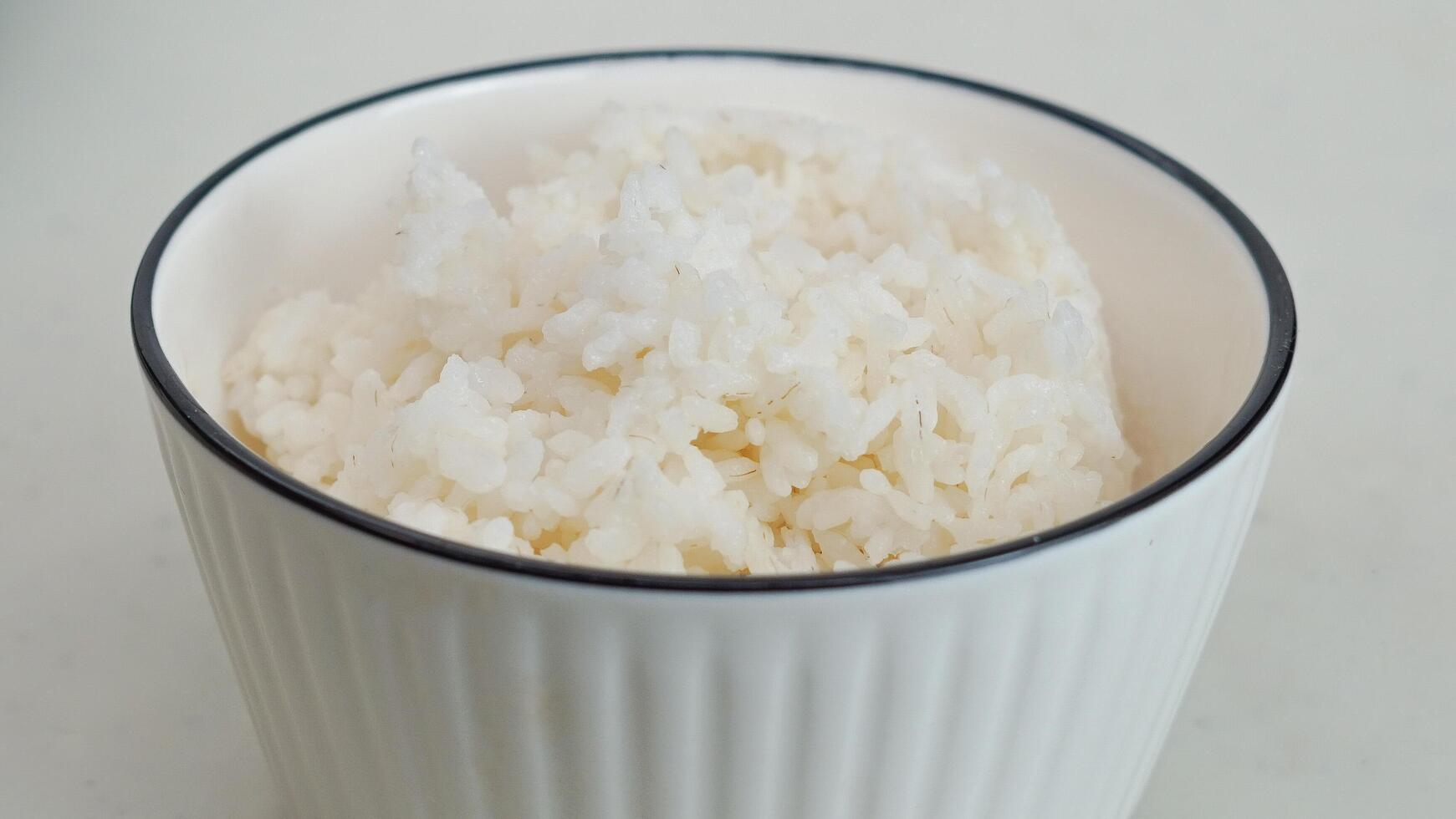 wit rijst- in een wit kom met eetstokjes foto