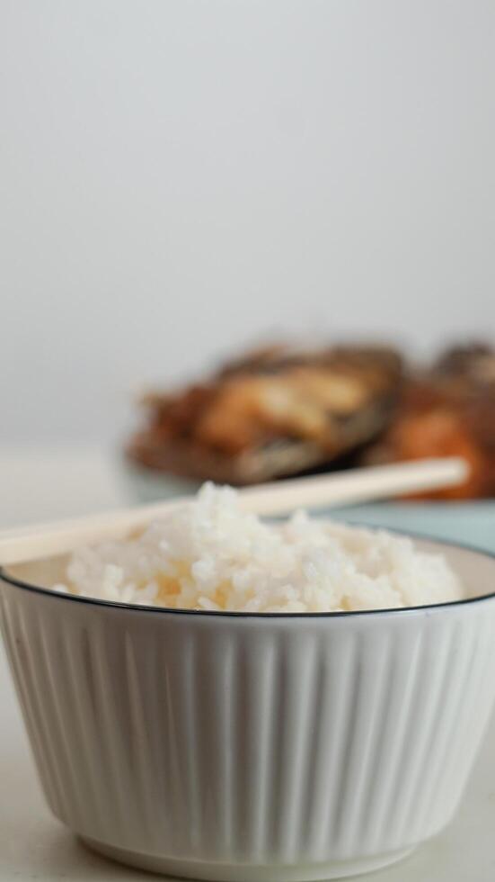 wit rijst- in een kom en gebakken vis Aan een wit bord zijn geserveerd Aan de tafel foto