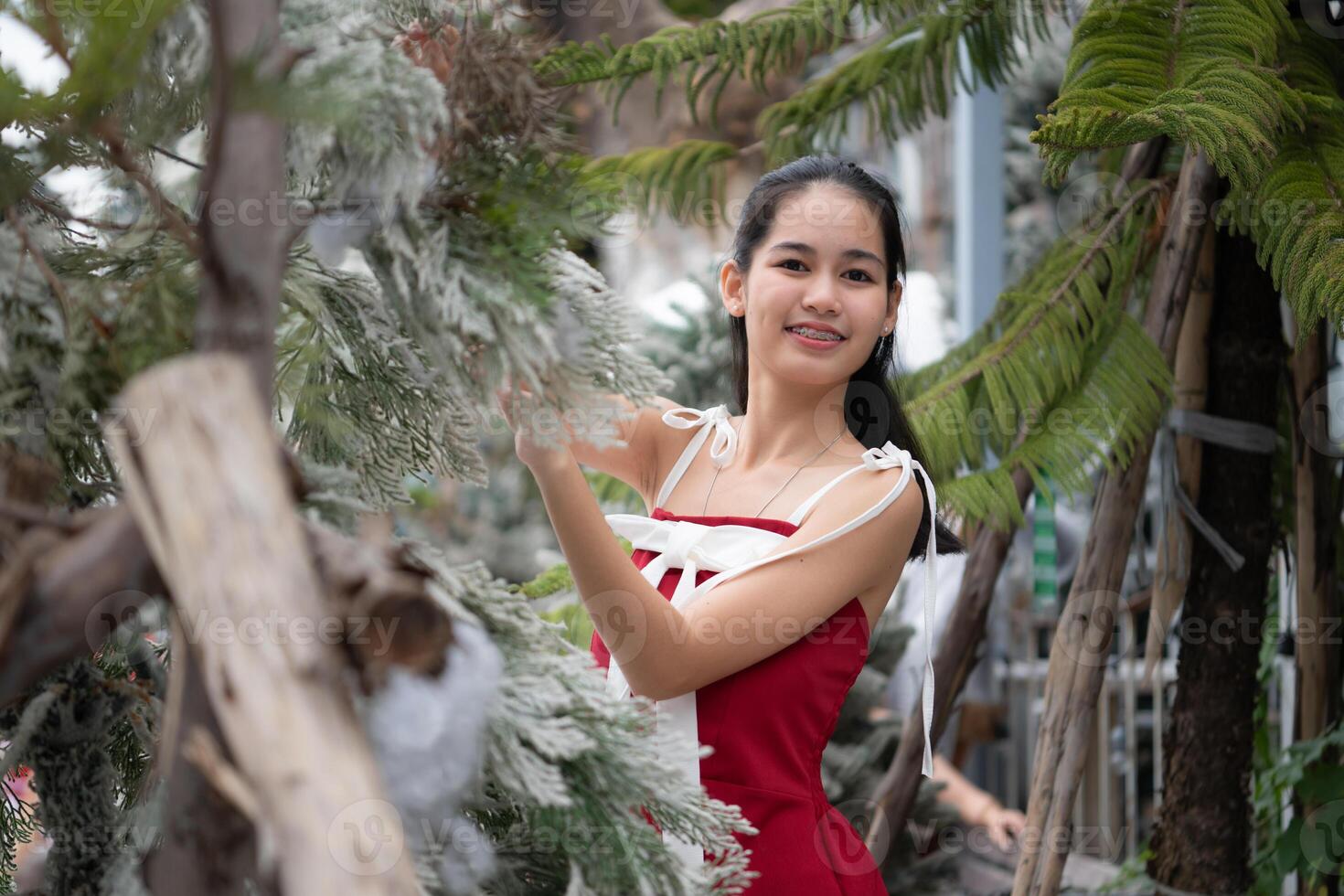 portret van tiener- meisje in een rood jurk ontspannen en glimlachen in een besneeuwd tuin. foto