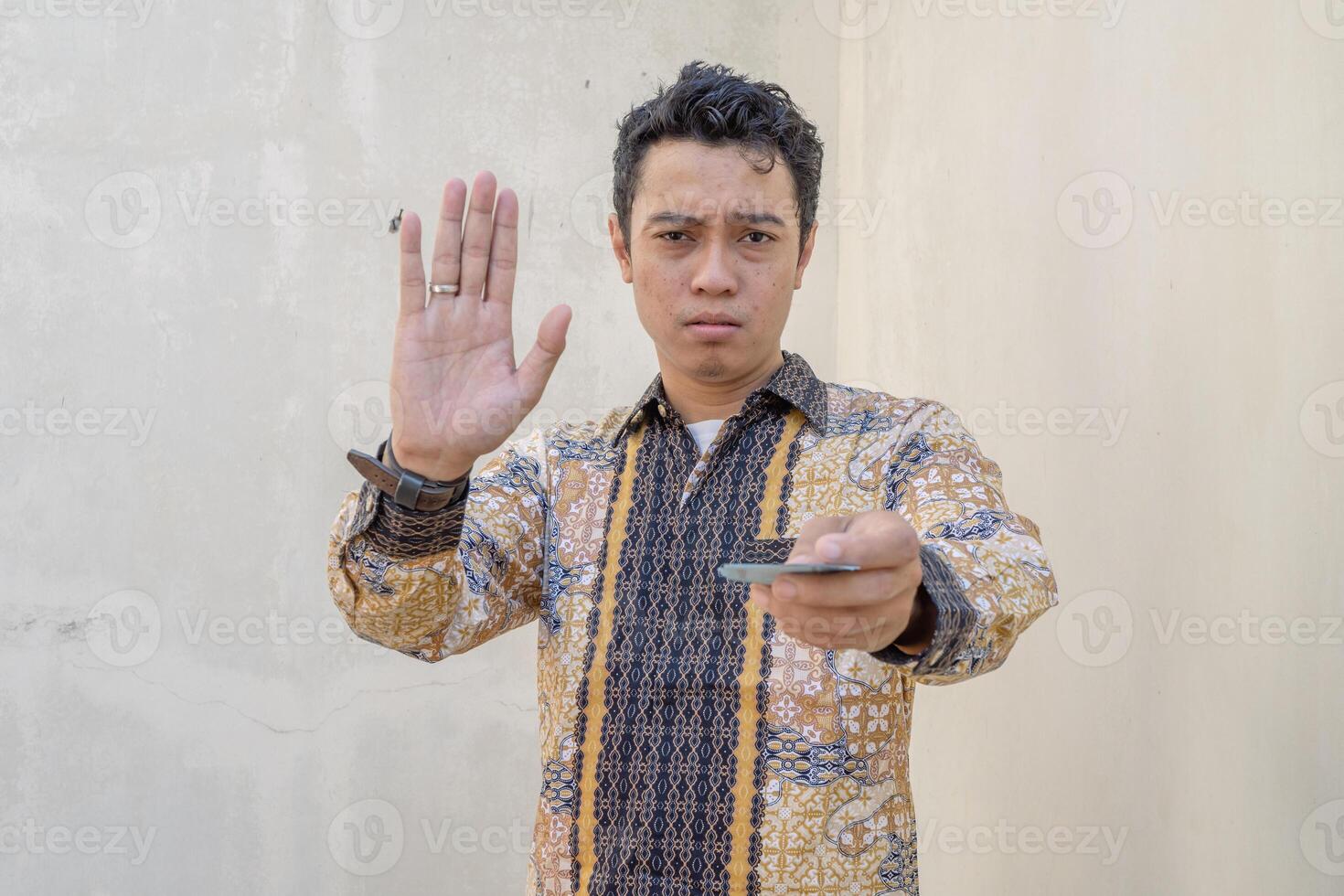 jong Indonesisch slijtage batik traditioneel cultuur van Indonesië afgekeurd houding en gebaar met houden de geld. de foto is geschikt naar gebruik voor dagelijks inhoud media en Mens uitdrukking reclame.