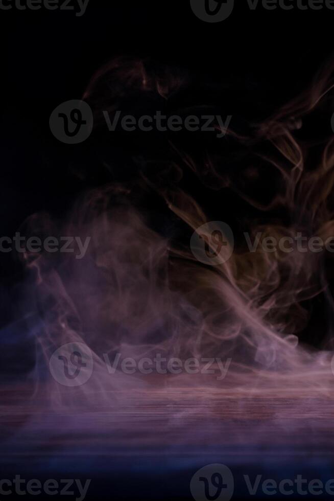 conceptueel beeld van veelkleurige rook geïsoleerd op donkere zwarte achtergrond en houten tafel. foto