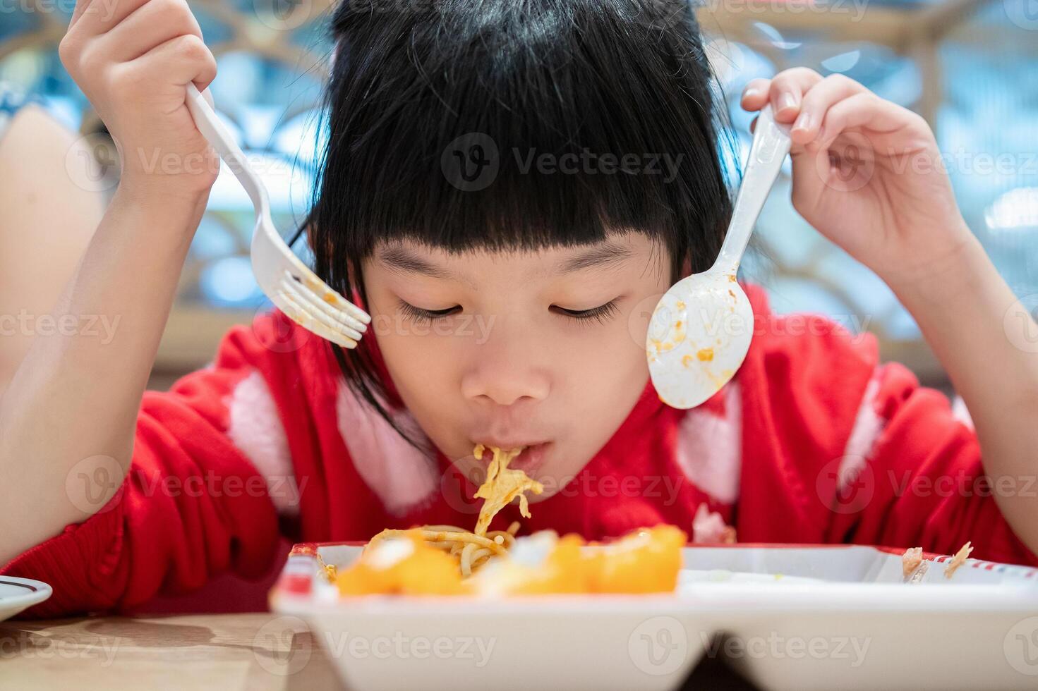 schattig weinig Aziatisch kind meisje aan het eten voedsel foto