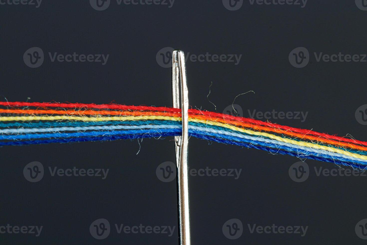 veelkleurig draden voor naaien in de het formulier van een regenboog voorbij gaan aan door een antiek naald- Aan een zwart achtergrond foto