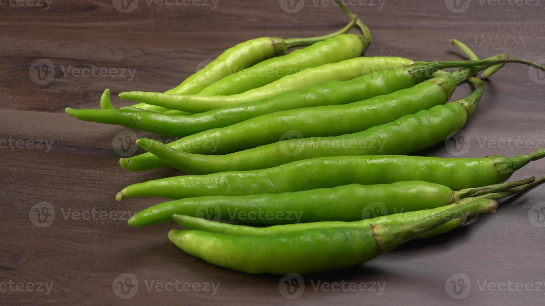 verse lange Indiase groene pepers op houten achtergrond. foto