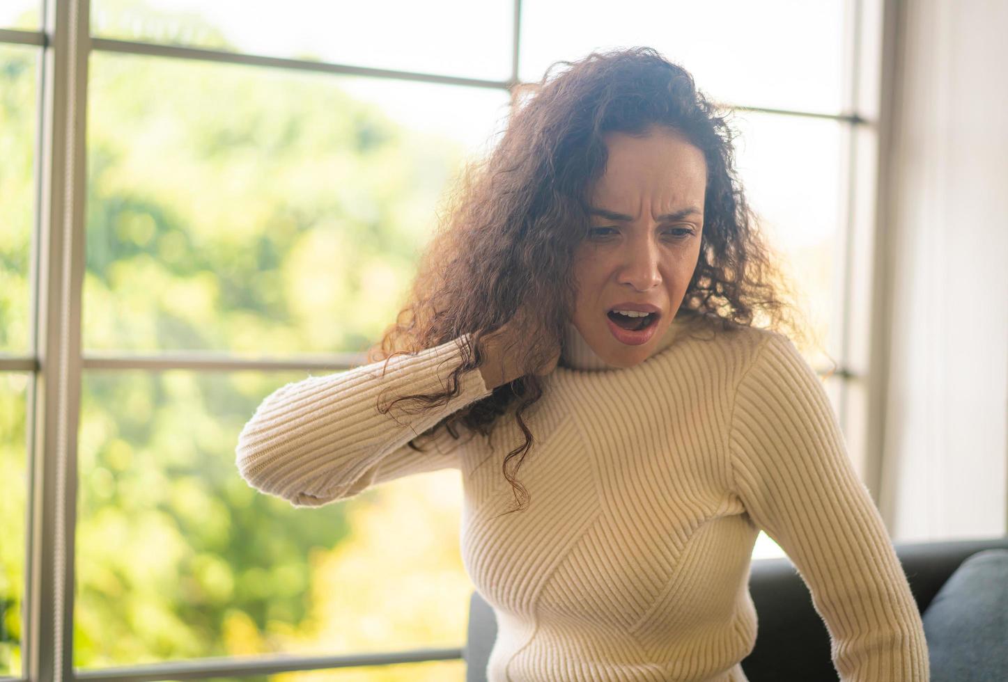 Latijnse vrouw zittend op de bank met nekpijn gevoel foto