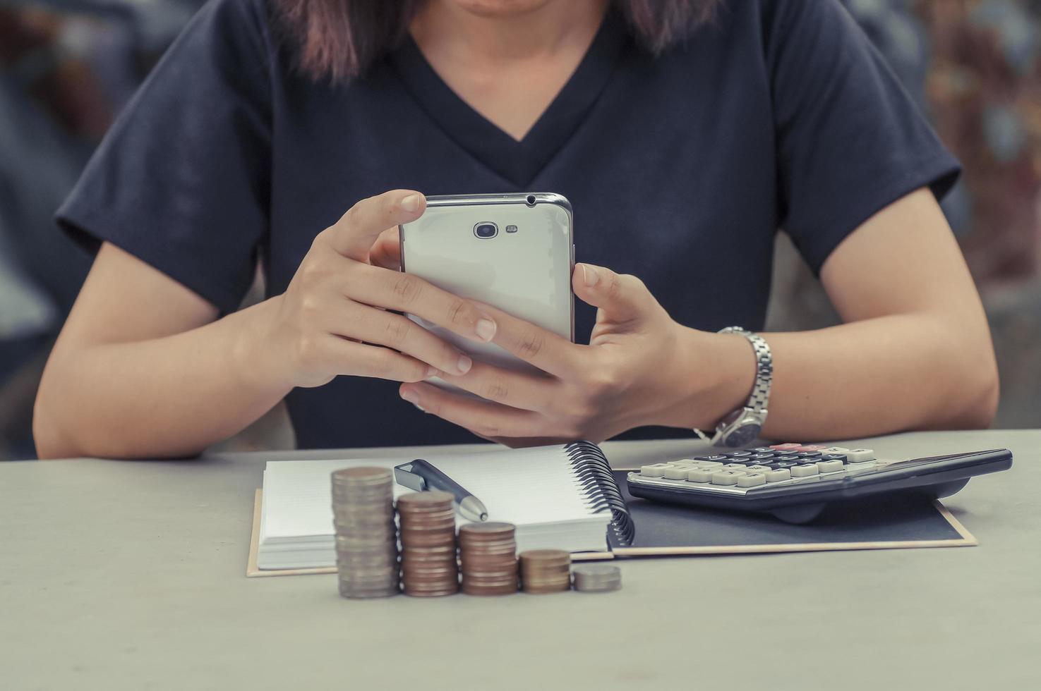 vrouwen gebruiken telefoon met boek, rekenmachine en munten op tafel foto