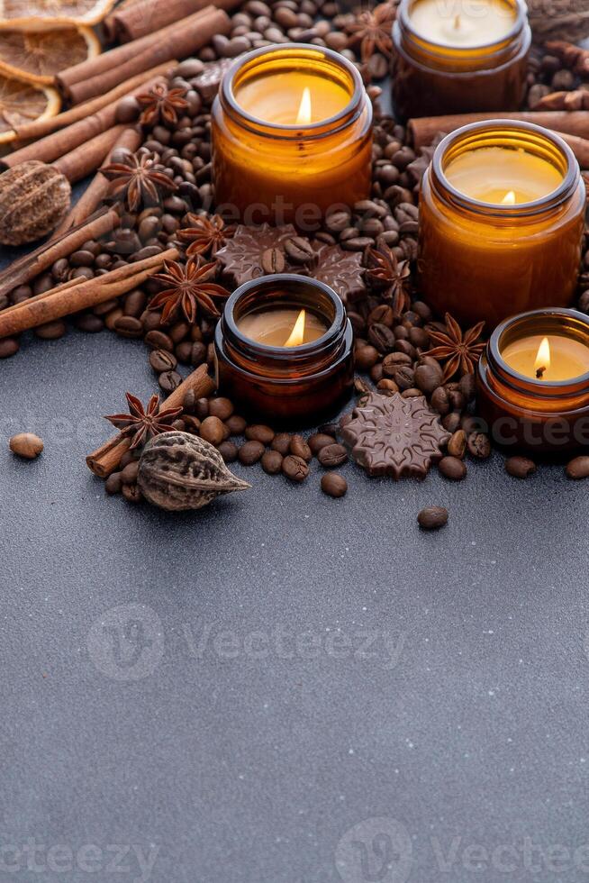 soja geparfumeerd kaars in een kan. koffie bonen, anijs, kaneel specerijen. de kaarsen zijn brandend. donker kopiëren ruimte achtergrond. foto