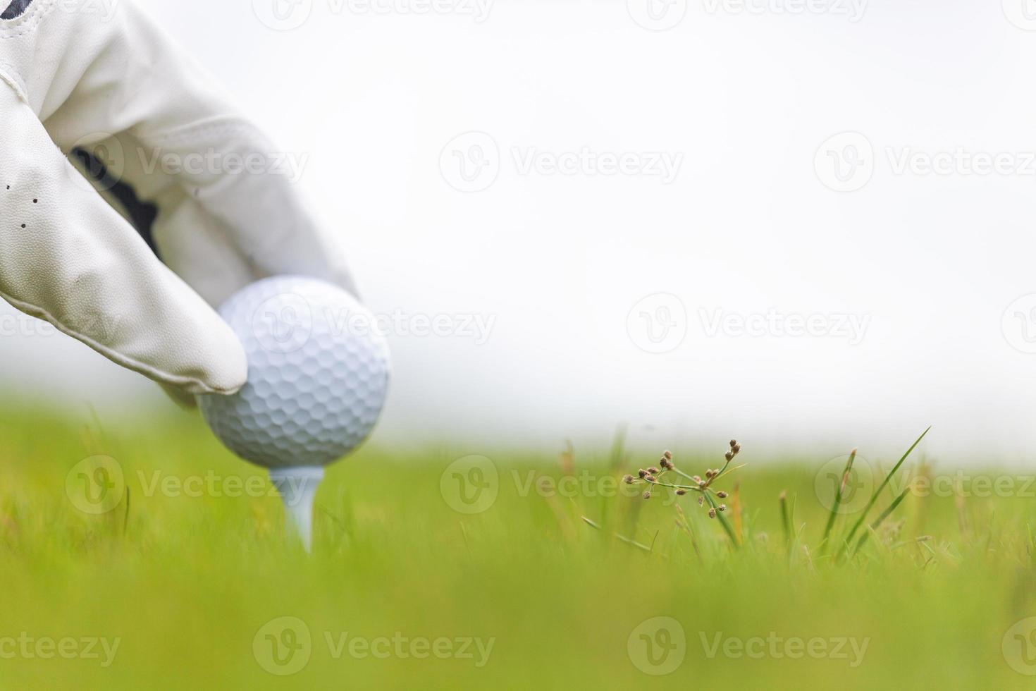 hand met golfbal met tee op golfbaan foto