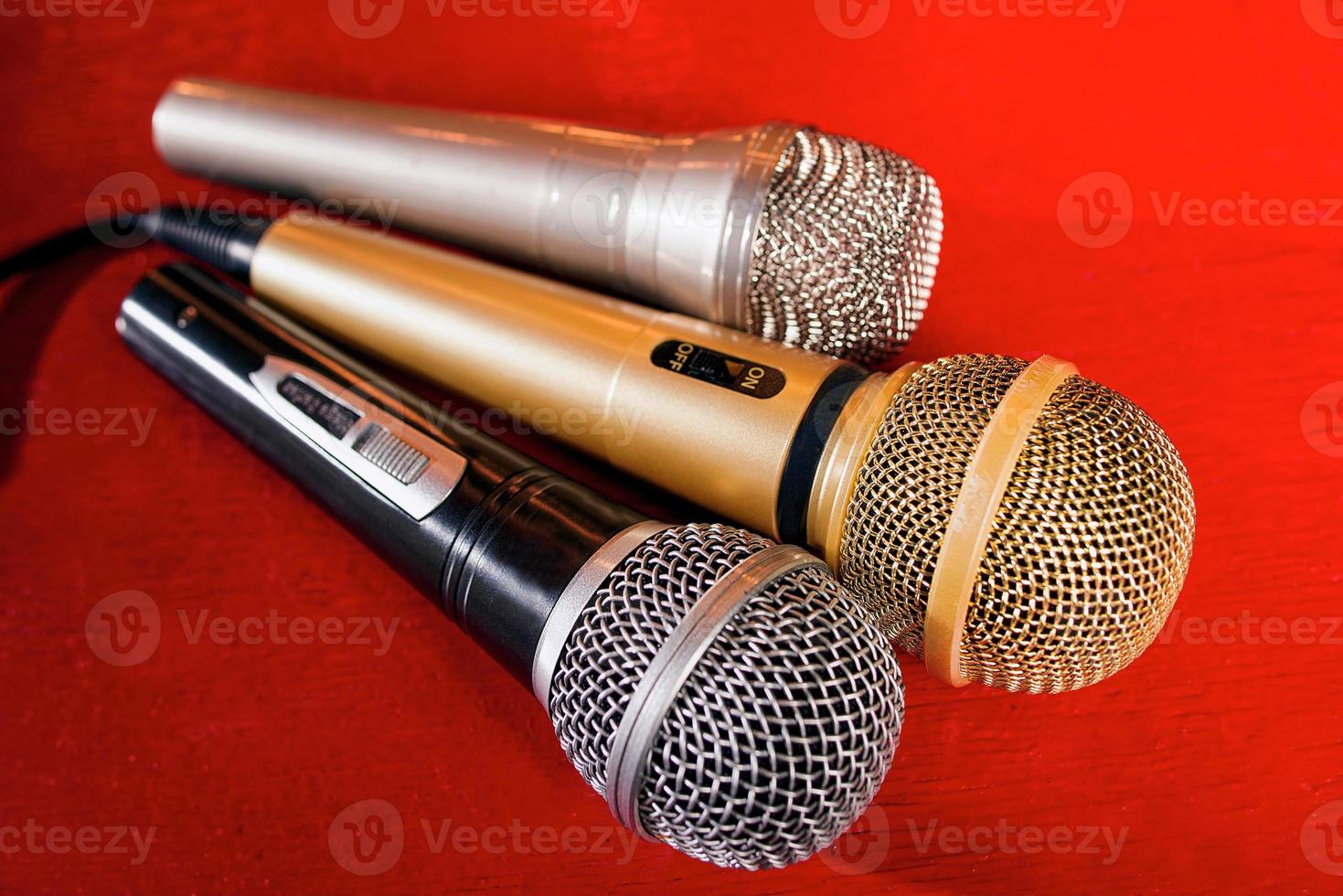 gouden, zilveren en bronzen microfoons op rode houten achtergrond foto