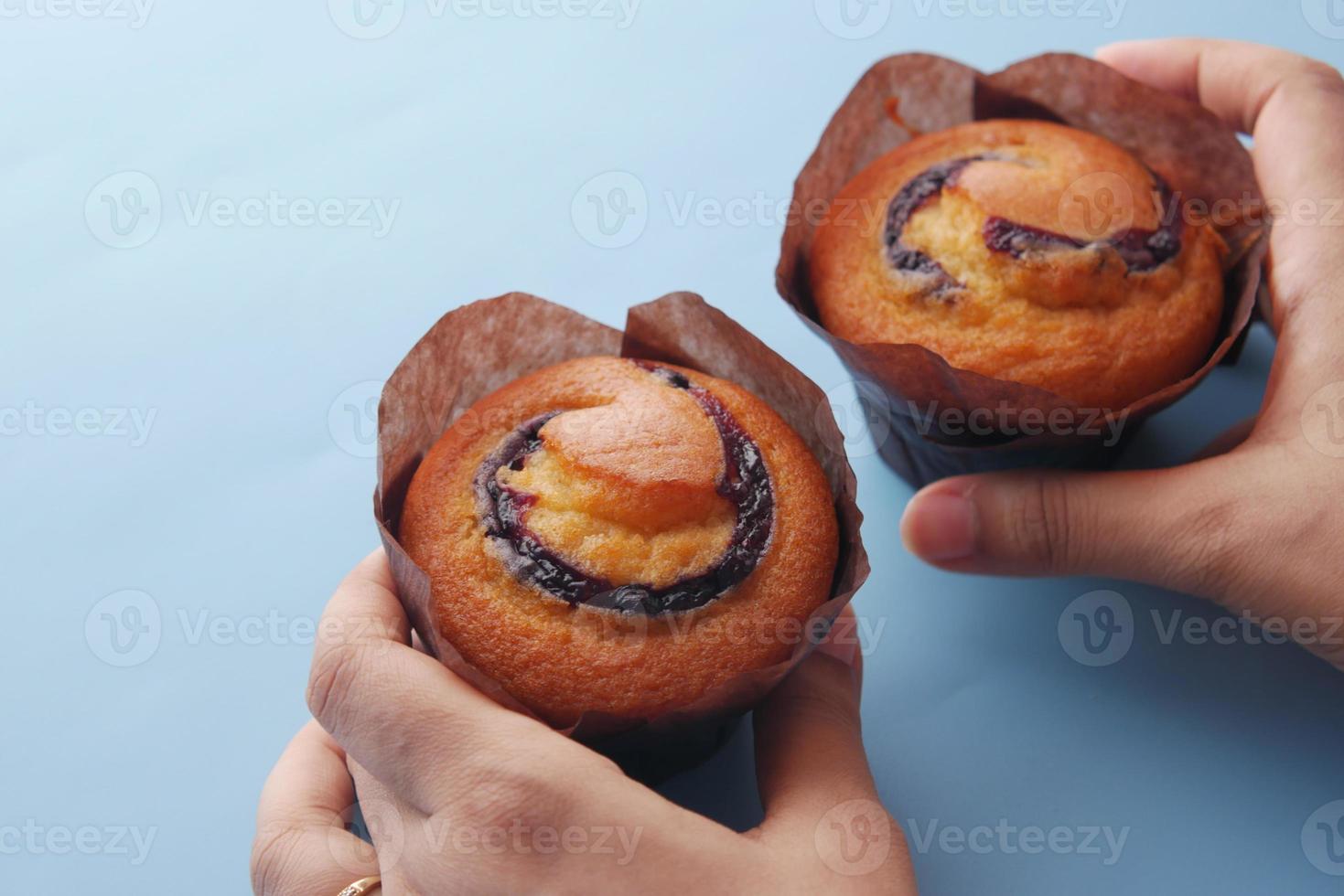 hand houden een bosbessenmuffins op tafel foto