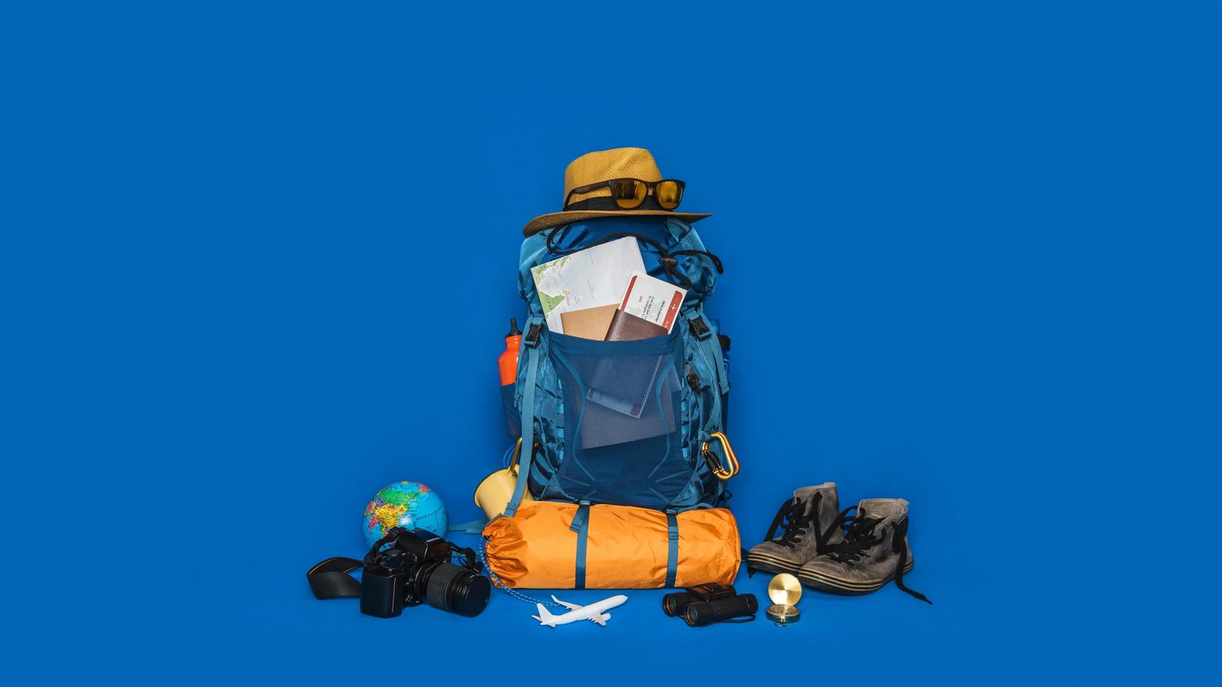 toeristische planning vakantie met behulp van wereldkaart met andere reisaccessoires in de buurt. concept bagage met accessoire voor reizigers vakantie op blauwe kleur achtergrond. reis rugzak foto