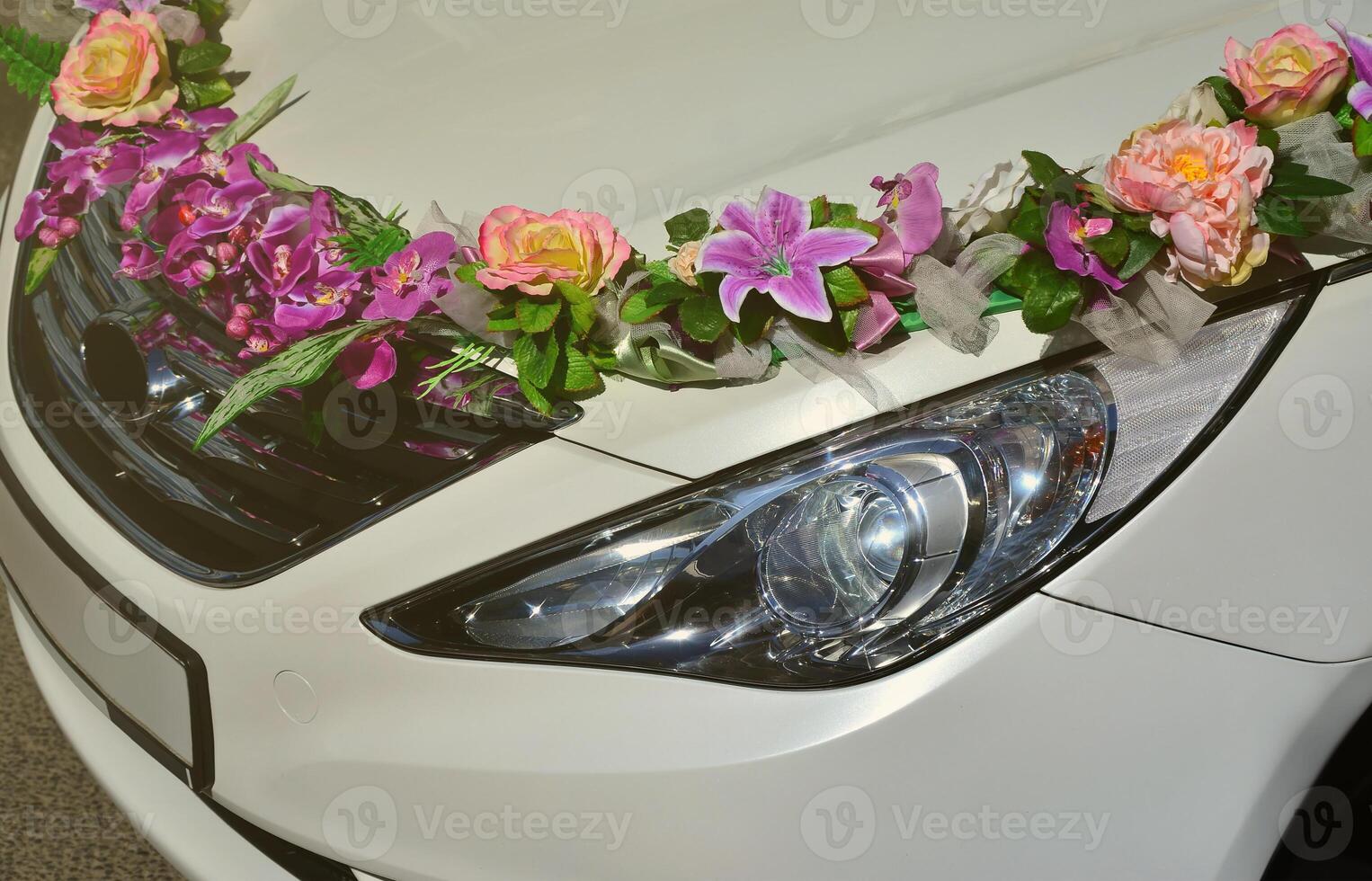 een gedetailleerd foto van de kap van de bruiloft auto, versierd met veel verschillend bloemen. de auto is bereid voor een bruiloft ceremonie