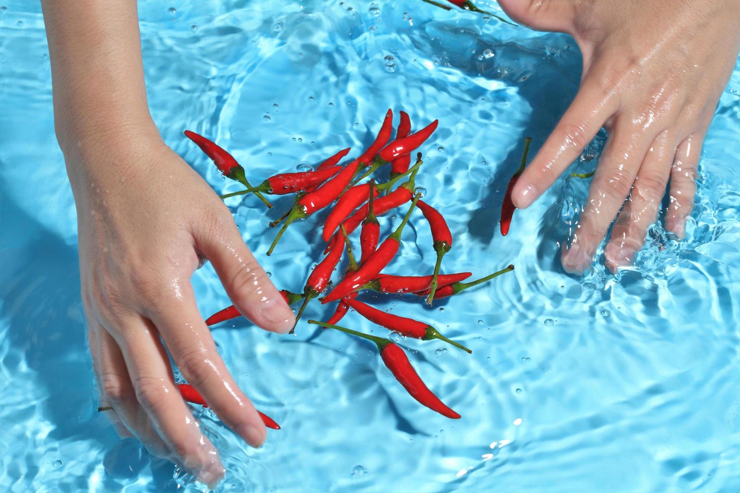 vrouw hand wassen vogel peper in water. groenten wassen voor het koken foto