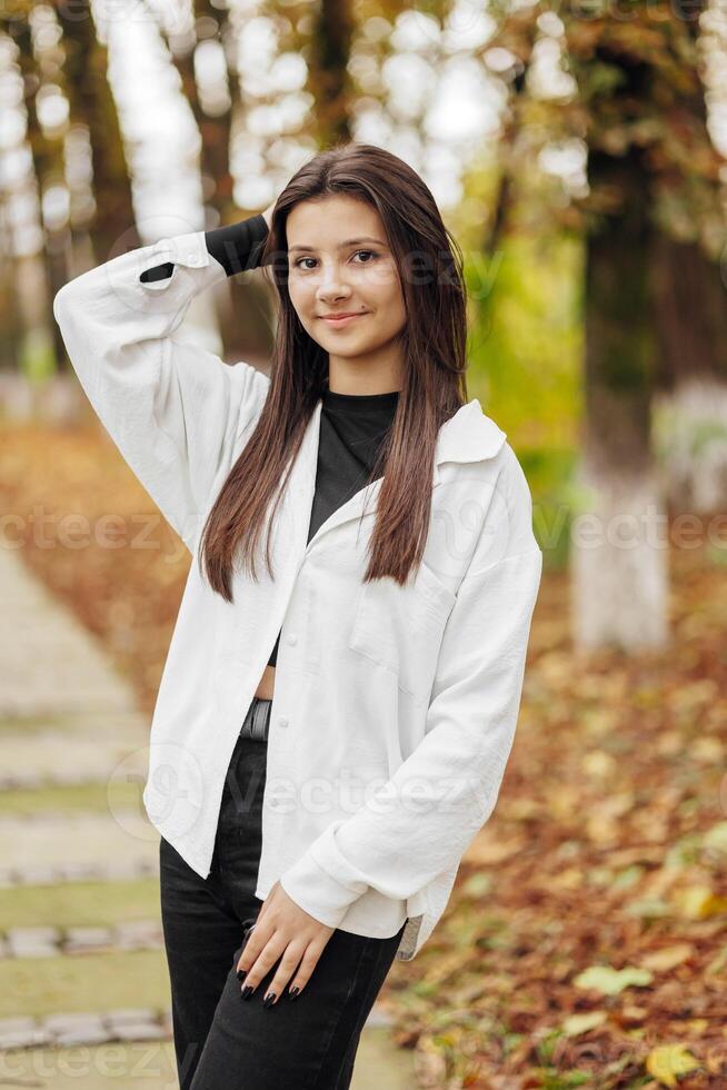 verticaal foto. mooi zorgeloos jong tiener- meisje in gewoontjes kleren. portret van een mooi meisje tegen de achtergrond van natuur met een wazig achtergrond. foto