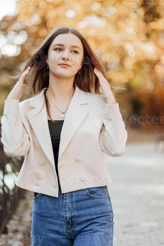 verticaal foto. mooi zorgeloos jong tiener- meisje in gewoontjes kleren. portret van een mooi meisje tegen de achtergrond van natuur met een wazig achtergrond. foto
