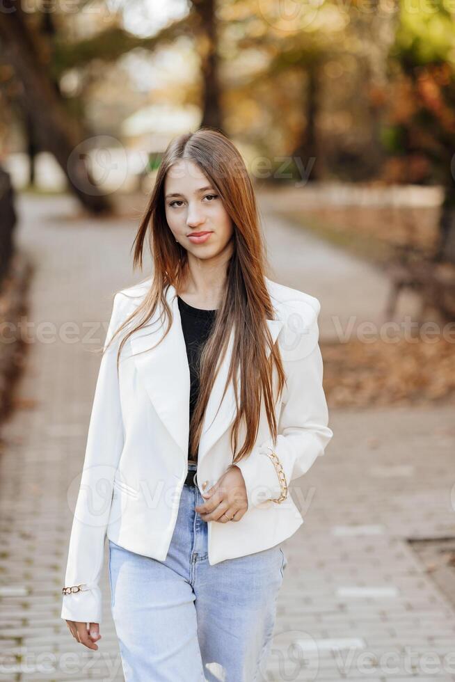 verticaal foto. mooi zorgeloos jong tiener- meisje in gewoontjes kleren. portret van een mooi meisje tegen de achtergrond van natuur met een wazig achtergrond. foto