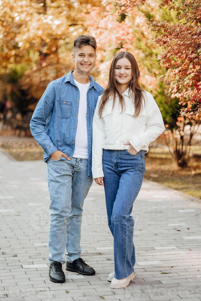 verticaal foto van twee tiener- vrienden gekleed in gewoontjes kleren staand De volgende naar elk andere tegen een achtergrond van natuur. het beste school- vrienden zijn klaar naar overwinnen iets naar bereiken de doel.