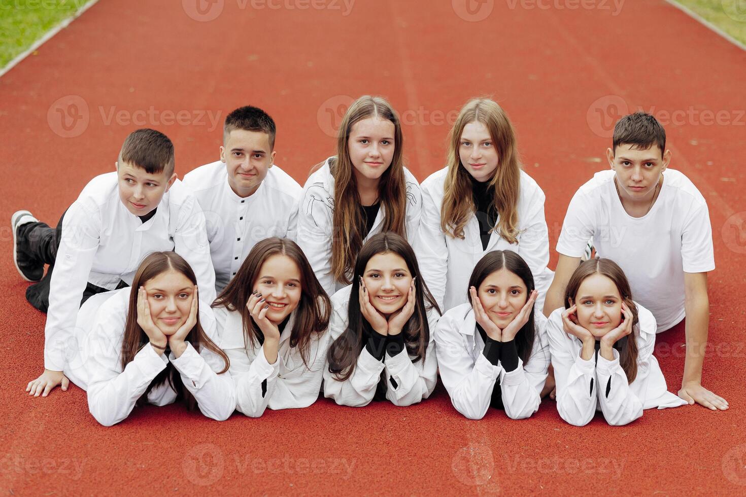 een groep van veel gelukkig tieners gekleed in de dezelfde kleding hebben pret en poseren in een stadion in de buurt een middelbare school. concept van vriendschap, momenten van geluk. school- vriendschap foto