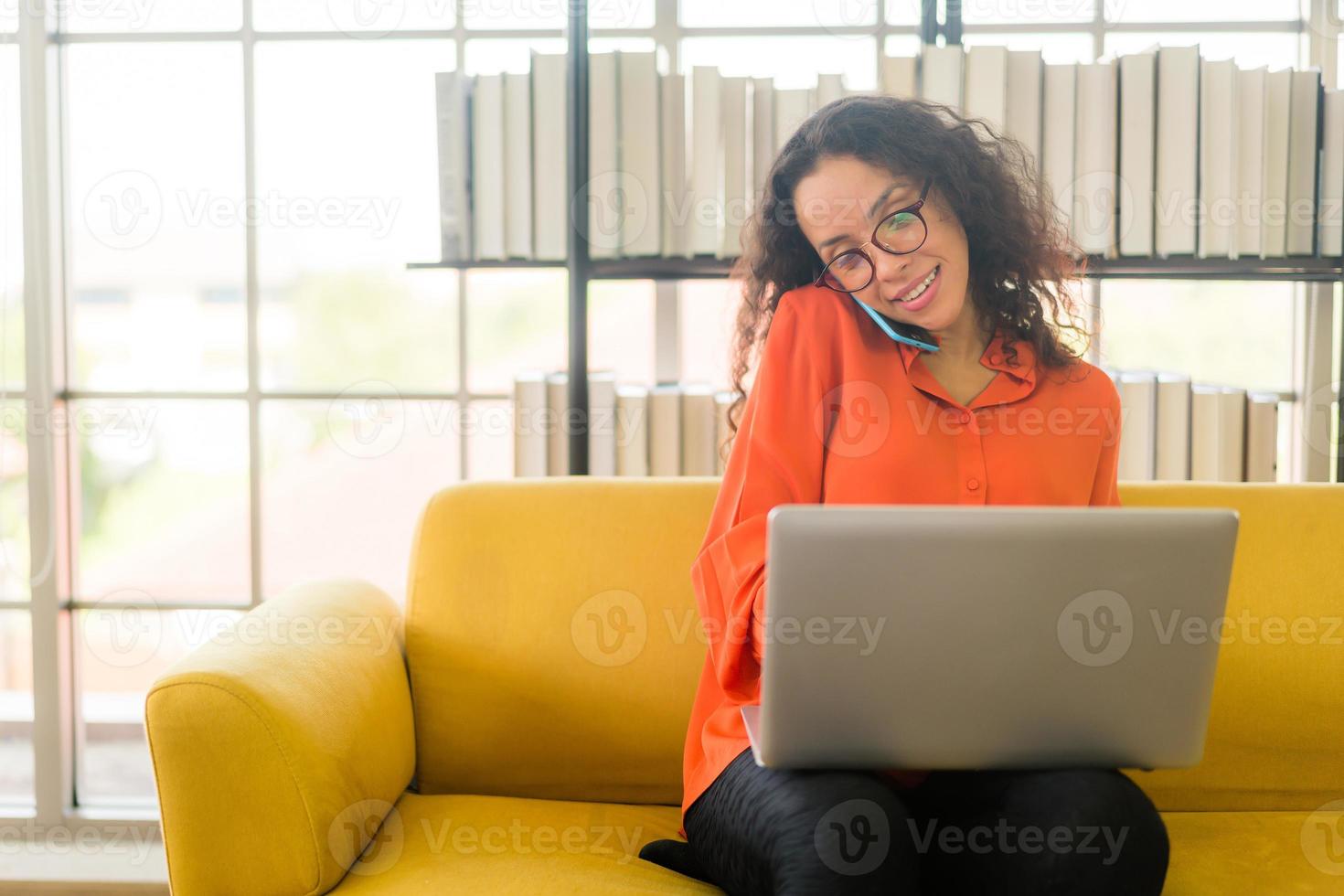 Latijnse vrouw die met laptop op bank werkt foto