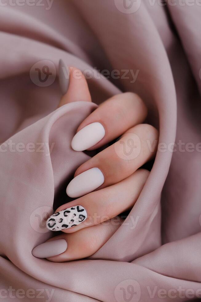 vrouw hand- met een mooi ovaal van vorm manicuren. herfst tendens, beige kleur polijsten met luipaard patroon Aan nagels met gel Pools, schellak. foto