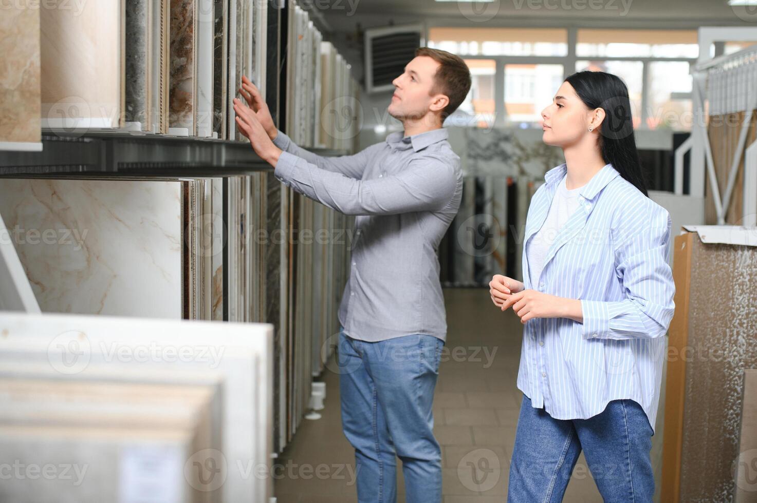 mooi jong paar kiezen keramisch tegels voor hun huis reparatie in de gebouw winkel foto