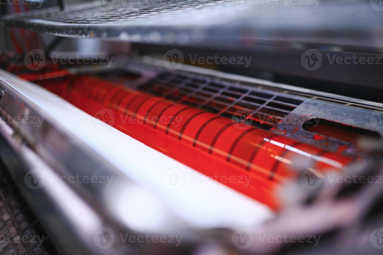 rood inkt Aan rollen van industrieel offset printer gedurende werk in typografie werkplaats foto