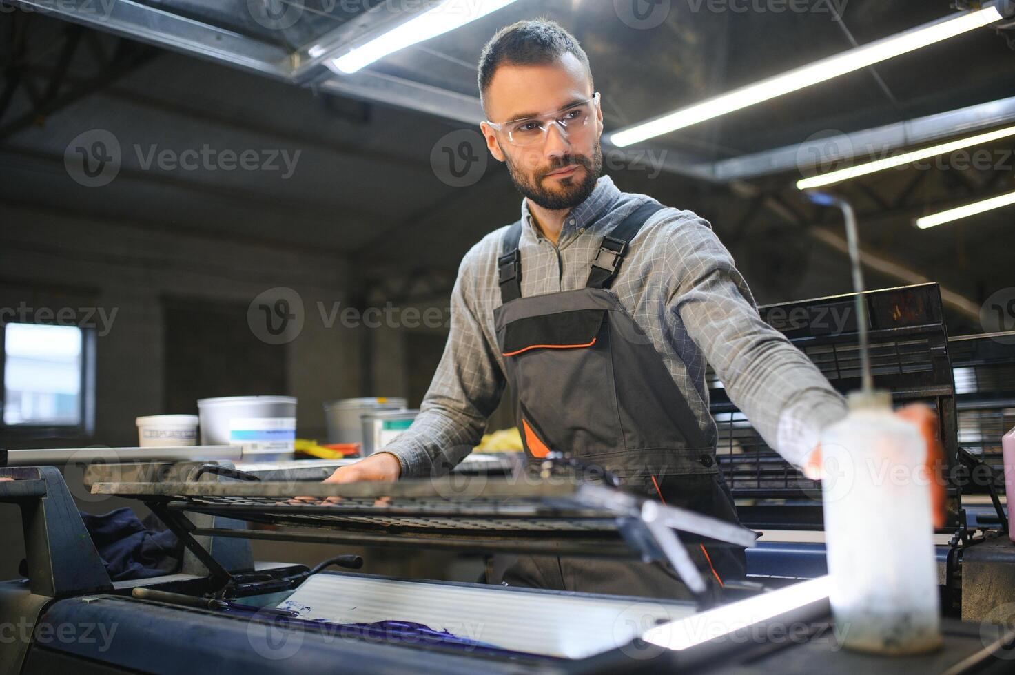 afdrukken arbeider proberen naar fix de probleem Aan computer naar bord machine in het drukken winkel foto