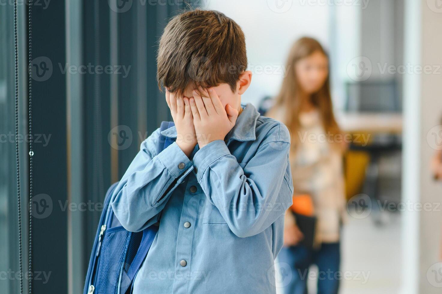 school- vrienden pesten een verdrietig jongen in gang Bij school- foto